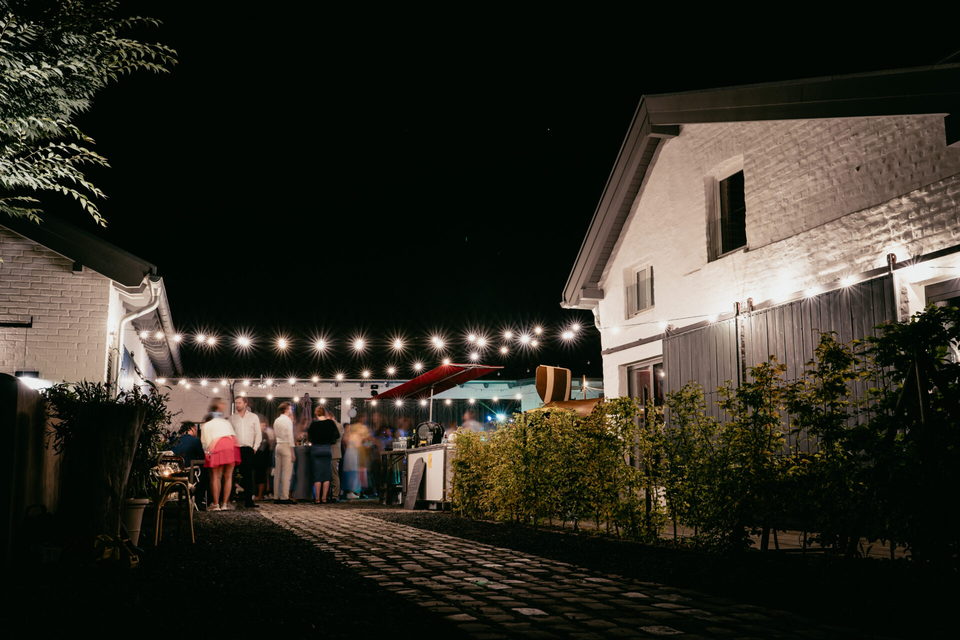 Hof am späten Abend, Gäste stehen unter einer Lichterkette