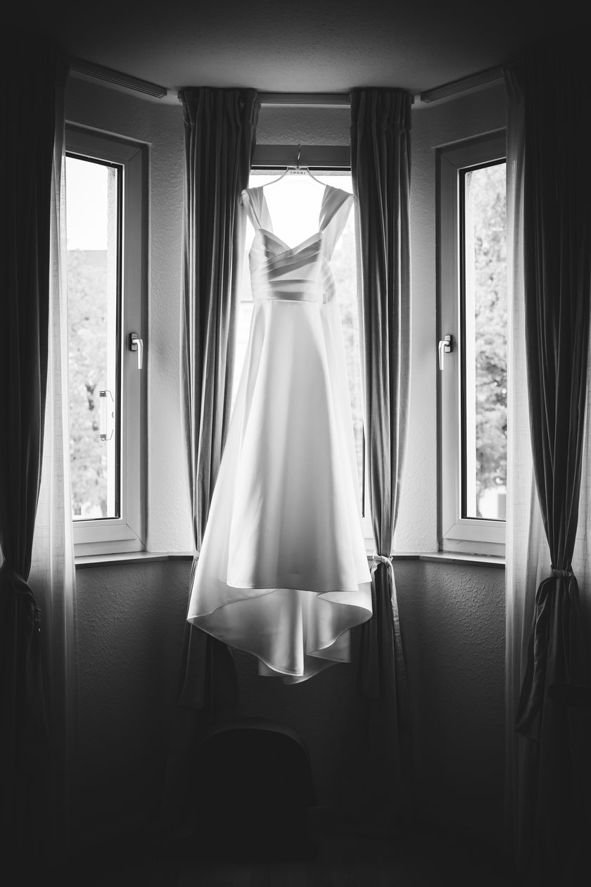 Das Brautkleid hängt in einem hohen Erkerfenster