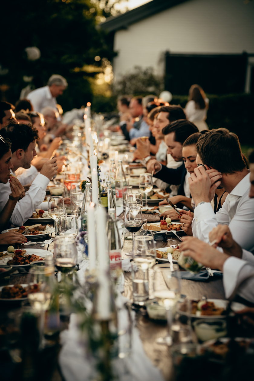 Lange Tafel am Abend, Kerzenlicht und Gäste im Gespräch