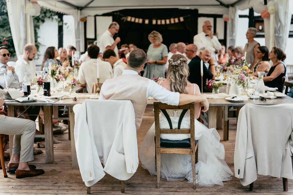 Hochzeitstafel unter einem offenen Zelt, Gäste an langen Tischen
